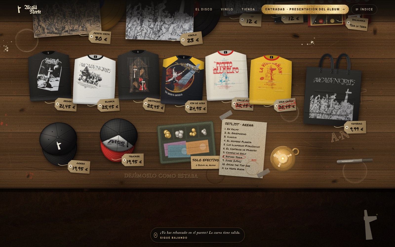 Capítulo V: el tenderete, una mesa de madera vista desde arriba con camisetas, vinilos, gorras y bolsa del grupo y sus etiquetas de precio a rotulador